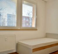 Schlafzimmer in einer 3-Zimmer-Wohnung mit großen Fenstern und einem Boden in Holzoptik.