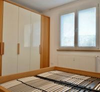 Schlafzimmer mit Bett ohne Matratze, Einbauschrank und Fenster, 3-Zimmer-Wohnung.
