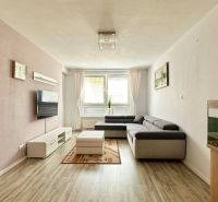 Wohnzimmer in einer 3-Zimmer-Wohnung mit Ecksofa und Boden in Holzoptik.