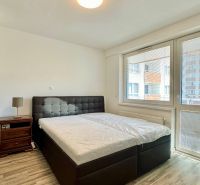 Schlafzimmer in einer 3-Zimmer-Wohnung mit Bett, Nachttisch und Boden in Holzoptik.