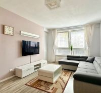 Wohnzimmer mit Ecksofa, Fernseher, Couchtisch und Boden mit Holzdekor.