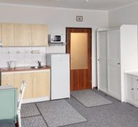 Küchenzeile und Möbel in einem Einzimmerapartment mit Teppich und weißer Kommode.