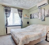 Schlafzimmer in einer 2-Zimmer-Wohnung mit Bett, Bildern und Klimaanlage an der Wand.