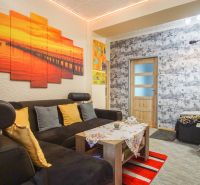 Wohnzimmer in einer Zweizimmerwohnung mit einem bequemen Sofa und bunten Dekorationen.