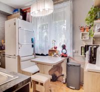 Küche in einer 2-Zimmer-Wohnung mit Essecke und Geräten, Boden mit Holzdekor.
