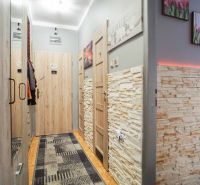 Der Flur in der 2-Zimmer-Wohnung mit Steinwänden und dekorativer Beleuchtung.
