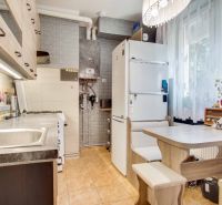 Küche in einer 2-Zimmer-Wohnung mit Geräten, Essecke und dekorativer Ziegelwand.