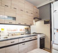 Küche in einer 2-Zimmer-Wohnung mit Holzdekor-Schränken und einem Gasherd.
