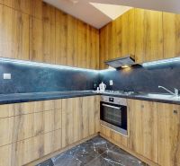 Küche mit Holzdekor-Schränken und Geräten in einer 4-Zimmer-Wohnung.