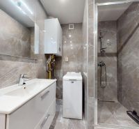 Badezimmer mit Dusche und Waschmaschine in einer 4-Zimmer-Wohnung.
