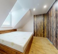 Schlafzimmer mit schräger Decke, Einbauschrank und Holzboden in einer 4-Zimmer-Wohnung.