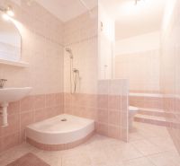 Badezimmer mit Fliesen und Duschkabine in einer Zweizimmerwohnung mit sanften Beigetönen.