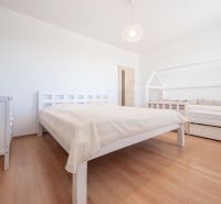 Schlafzimmer mit Holzboden, Doppelbett und Kinderbett.