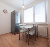 Küche mit Holzboden, Essbereich und Geräten in einer Zweizimmerwohnung.