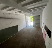 Innenraum einer Garage mit Betonboden und offenen Blechttüren.