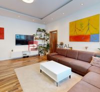 Wohnzimmer in einer 3-Zimmer-Wohnung mit Holzboden, Sofa und Bildern an den Wänden.