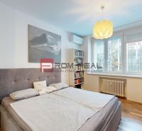 Schlafzimmer mit grauem Bett, Schreibtisch und Regal in einer 3-Zimmer-Wohnung.