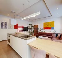 Küche und Wohnzimmer in einer 3-Zimmer-Wohnung mit Kunst an den Wänden und einem bequemen Sofa.