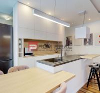 Küche in einer 3-Zimmer-Wohnung mit Spüle, Barhockern und Boden mit Holzdekor.