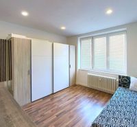 Ein Zimmer mit Bett, Schrank und einem Boden in Holzoptik im Ferienapartment.