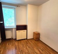 Ein Zimmer mit Holzboden in einer Einzimmerwohnung mit hellen Möbeln.
