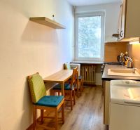 Küche mit zwei Stühlen und Holzboden in einer Zweizimmerwohnung.