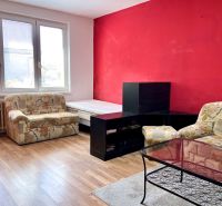 Wohnzimmer in einer 2-Zimmer-Wohnung mit Sesseln, einem Tisch und einem Boden in Holzoptik.