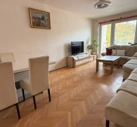 Wohnzimmer in einer 4-Zimmer-Wohnung mit großem Sofa, Esstisch und Holzboden.