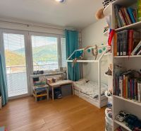 Kinderzimmer mit Bett und Regalen in einer 4-Zimmer-Wohnung, Boden mit Holzdekor.