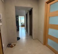 Ein Flur mit hellen Fliesen und Holztüren in einer Vierzimmerwohnung.
