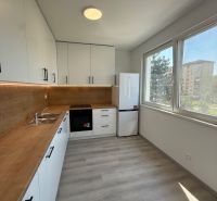 Küche in einer 3-Zimmer-Wohnung mit weißen Schränken und einem Boden in Holzoptik.