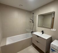 Badezimmer in einer 3-Zimmer-Wohnung mit Badewanne, Waschbecken und Waschmaschine, beige Fliesen.