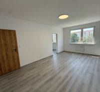 Zimmer in einer 3-Zimmer-Wohnung mit Holzboden, weißen Wänden und einem Fenster.