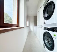 Praktische Waschküche in einer 3-Zimmer-Wohnung mit Waschmaschine und Trockner auf weißem Boden.