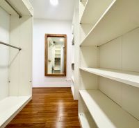 Ein Kleiderschrank in einer 3-Zimmer-Wohnung mit Regalen und einem Boden in Holzoptik.