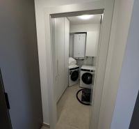 Waschküche mit einer weißen Waschmaschine und einem Trockner in einer 3-Zimmer-Wohnung.