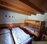 Ein Zimmer mit zwei Betten und einem Etagenbett, Holzwand- und Deckenverkleidung.