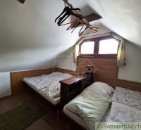 Dachboden mit zwei Betten, Holzboden, Kleiderhaken, kleines Fenster, niedrige Decke.