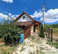Eine Hütte in Gbelce, umgeben von Grün und Bäumen unter blauem Himmel.