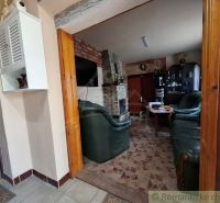 Wohnzimmer in einer Hütte mit Kamin, Ledersitzgruppe und weißem Schrank.