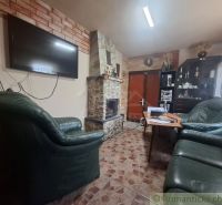 Ein Kamin aus Stein und Ledersofas in einer Hütte mit einem Boden im Fliesenstil.