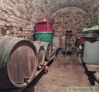 Ein steinerner Keller in der Hütte mit Holzfässern und Plastikbehältern.