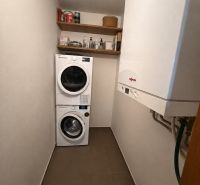 Waschküche in einer 3-Zimmer-Wohnung mit Waschmaschine, Trockner, Regalen und Gastherme.