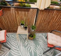 Balkon mit Blumen und Stühlen mit Kissen in einer 3-Zimmer-Wohnung.