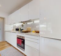 Küche mit Geräten, weißen Schränken und Holzboden in einer 3-Zimmer-Wohnung.