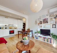 Wohnzimmer einer 3-Zimmer-Wohnung mit offener Küche und Boden in Holzoptik.