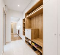Flur mit Schuhschrank und Kleiderschrank in einer 3-Zimmer-Wohnung, Holzdekor und weiße Elemente.