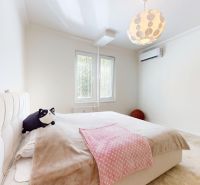 Helles Schlafzimmer mit großem Bett, zwei Fenstern und Klimaanlage in einer 3-Zimmer-Wohnung.