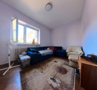 Wohnzimmer in einem Einfamilienhaus mit einem blauen Sofa, einem Sessel und einem Teppich auf einem Boden mit Holzdekor.