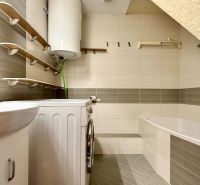 Badezimmer in einer 2-Zimmer-Wohnung mit Badewanne, Waschbecken, Waschmaschine und Boiler.